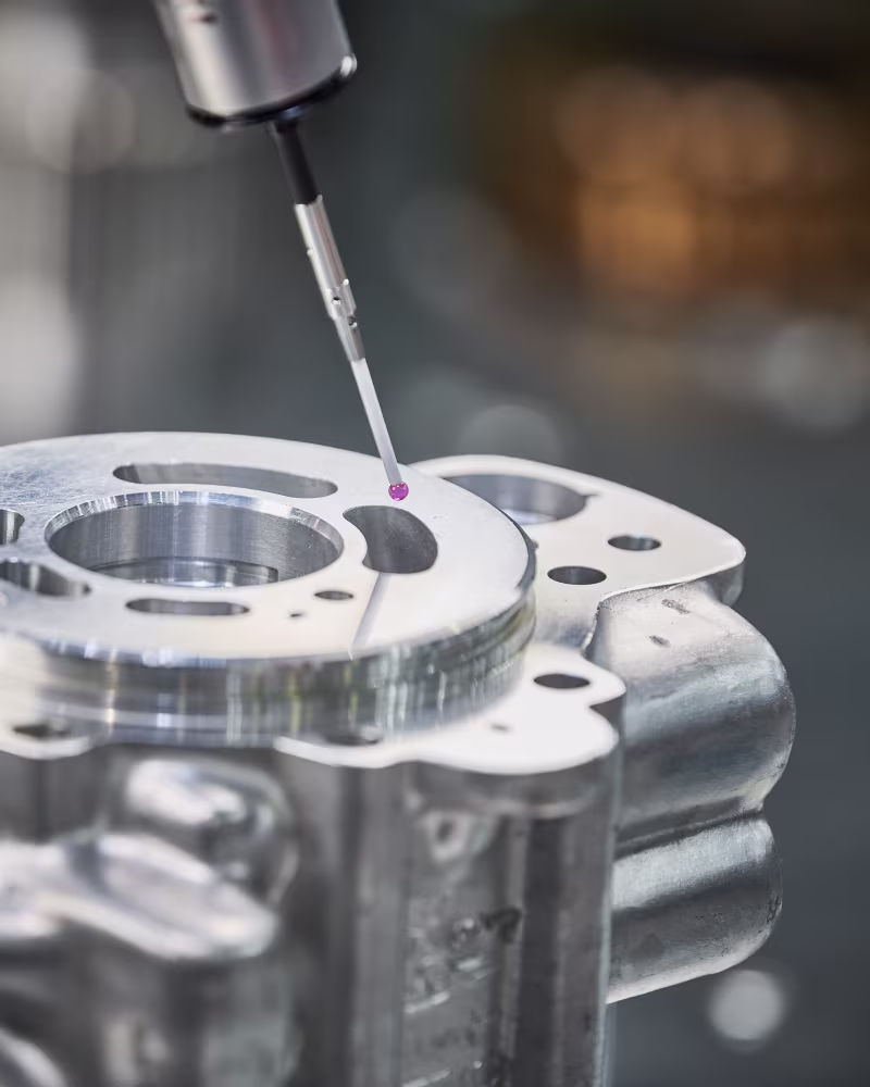 Koordinatenmessgerät misst präzise einen Bereich auf einem Metallteil mit rotem Sensorkopf.